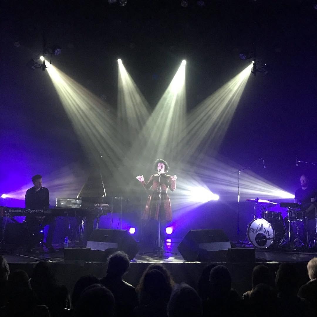 Emel Mathlouthi performing on stage with dramatic purple lighting